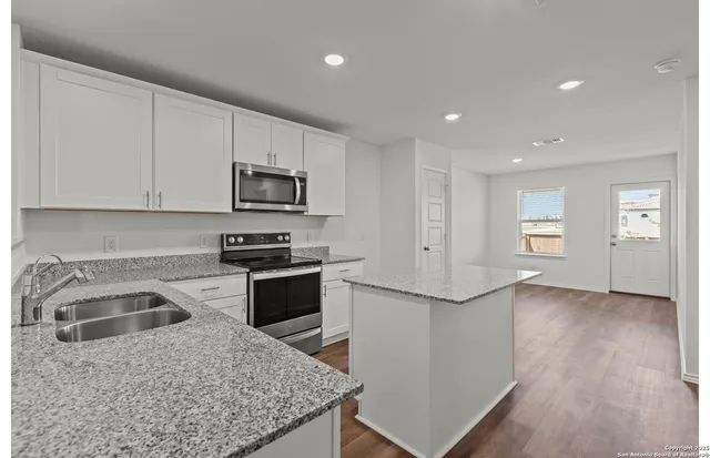 a kitchen with granite countertop white cabinets and stainless steel appliances