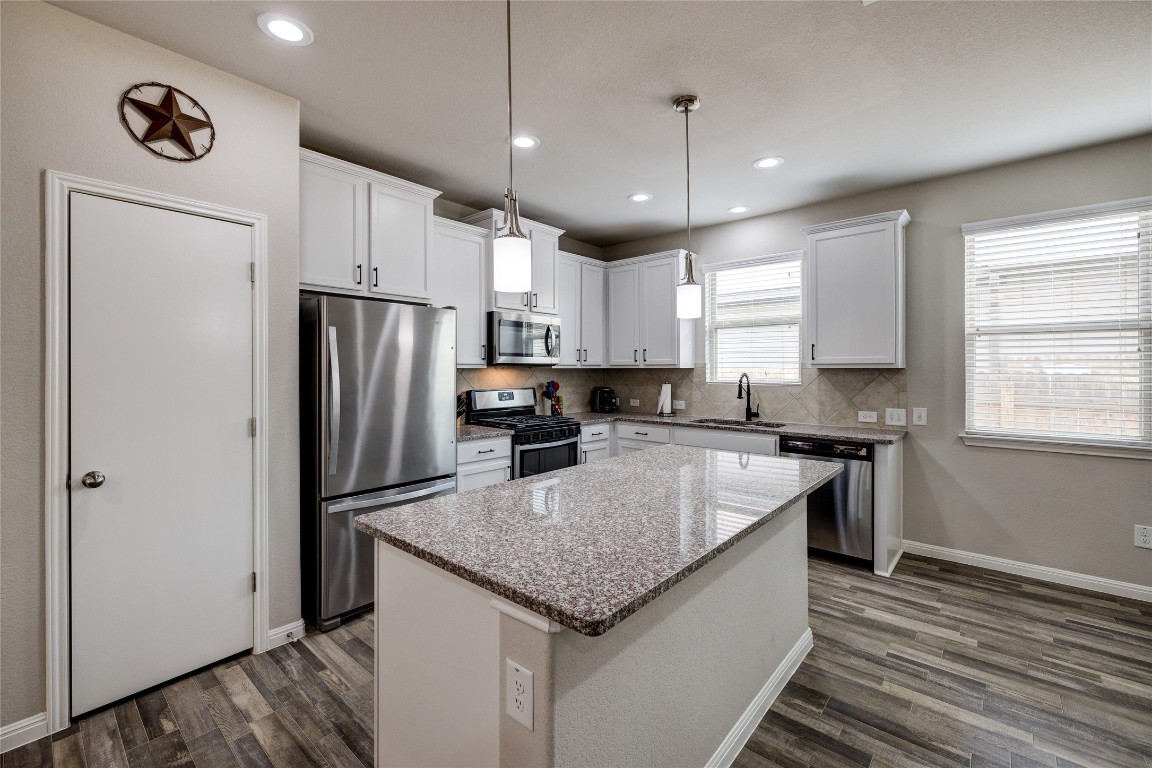 128 Shearwater Lane Leander, TX 78641 - Photo 15 of 30 a kitchen with stainless steel appliances granite countertop a refrigerator a sink dishwasher a stove and white cabinets with wooden floor