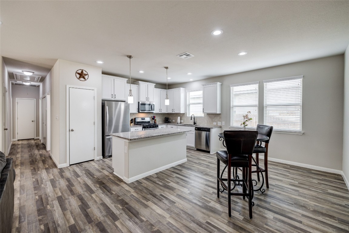 128 Shearwater Lane Leander, TX 78641 - Photo 17 of 30 a kitchen with stainless steel appliances a refrigerator a stove a sink dishwasher and a dining table with wooden floor