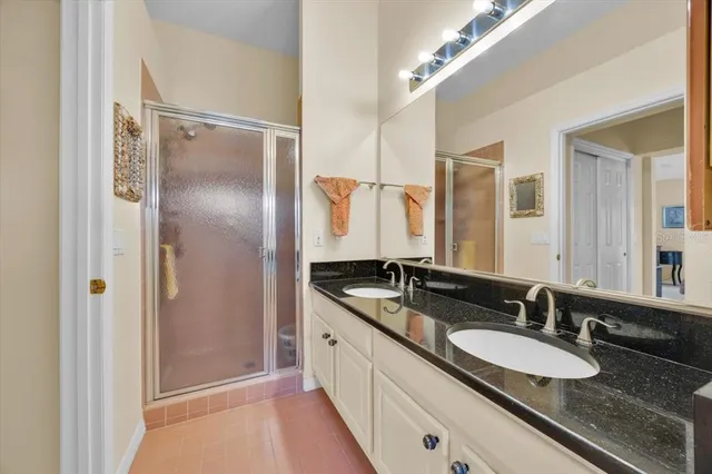 a bathroom with a granite countertop double vanity sink and mirror