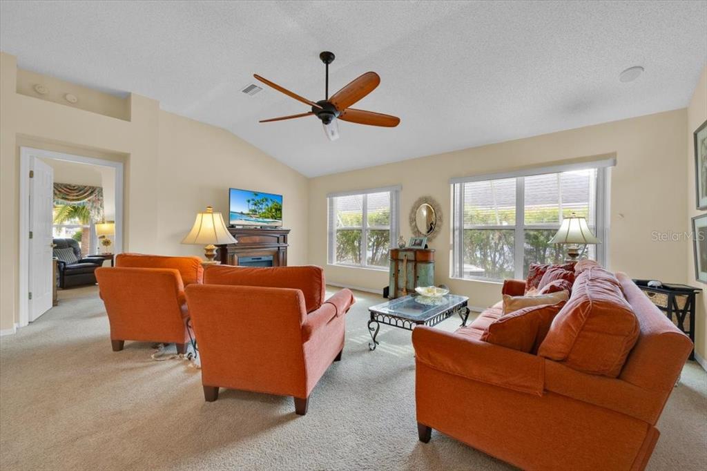 802 Miranda Way The Villages, FL 32159 - Photo 7 of 29 a living room with furniture a ceiling fan a fireplace and a large window