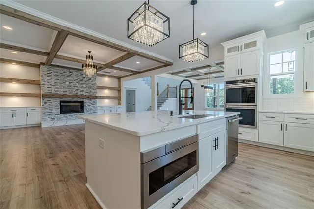 a large kitchen with stainless steel appliances a large center island wooden floor and a window