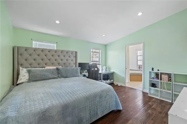 a large bedroom with a bed and wooden floor