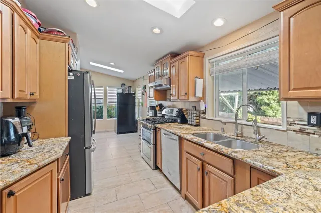 a kitchen with stainless steel appliances granite countertop a sink a stove and a refrigerator