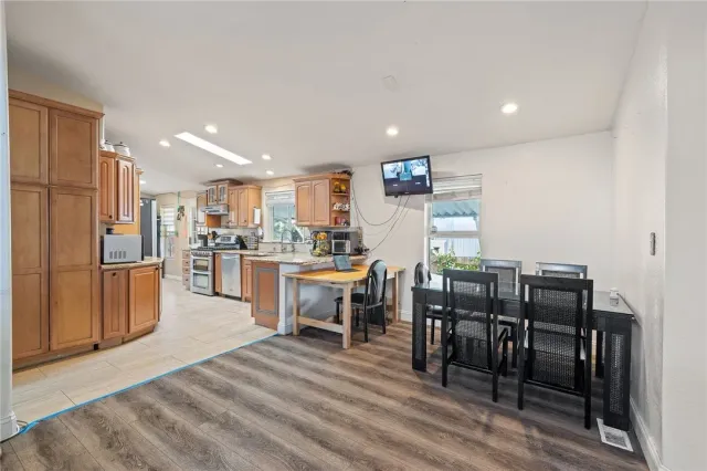 a open kitchen with stainless steel appliances kitchen island granite countertop a table chairs and a refrigerator