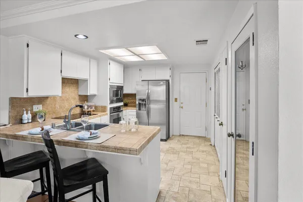 a kitchen with a dining table chairs and refrigerator