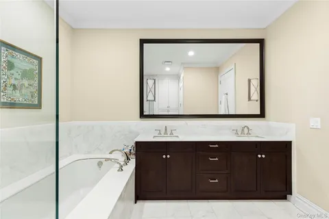 a bathroom with a tub a double vanity sink and mirror