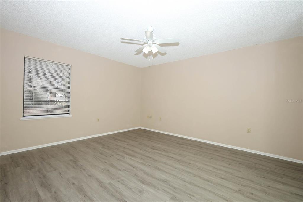 3240 Littlefield Street Deltona, FL 32738 - Photo 9 of 18 an empty room with wooden floor ceiling fan and window