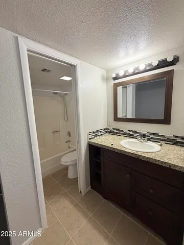 a bathroom with a granite countertop sink toilet and mirror