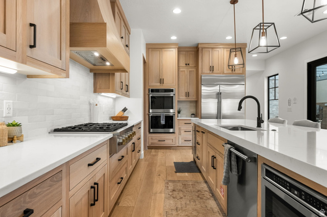 5354 Cyan Lane St. George, UT 84790 - Photo 4 of 45 Kitchen featuring light stone counters, light wood finished floors, stainless steel appliances, pendant lighting, and light wood finish cabinets