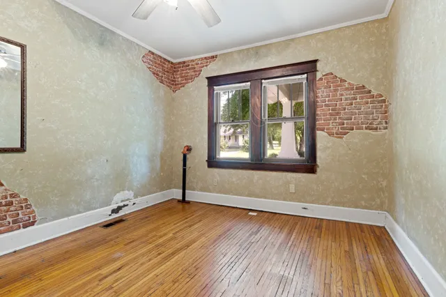 a view of an empty room with wooden floor and a window