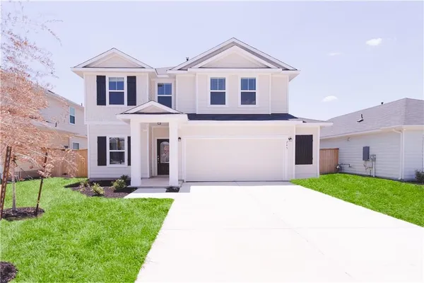 a front view of a house with a yard and trees