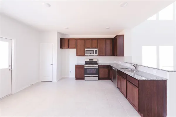 a kitchen with stainless steel appliances granite countertop a stove a sink and a refrigerator with wooden cabinets