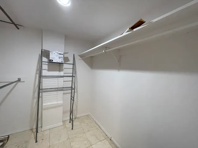 a view of walk in closet with empty racks
