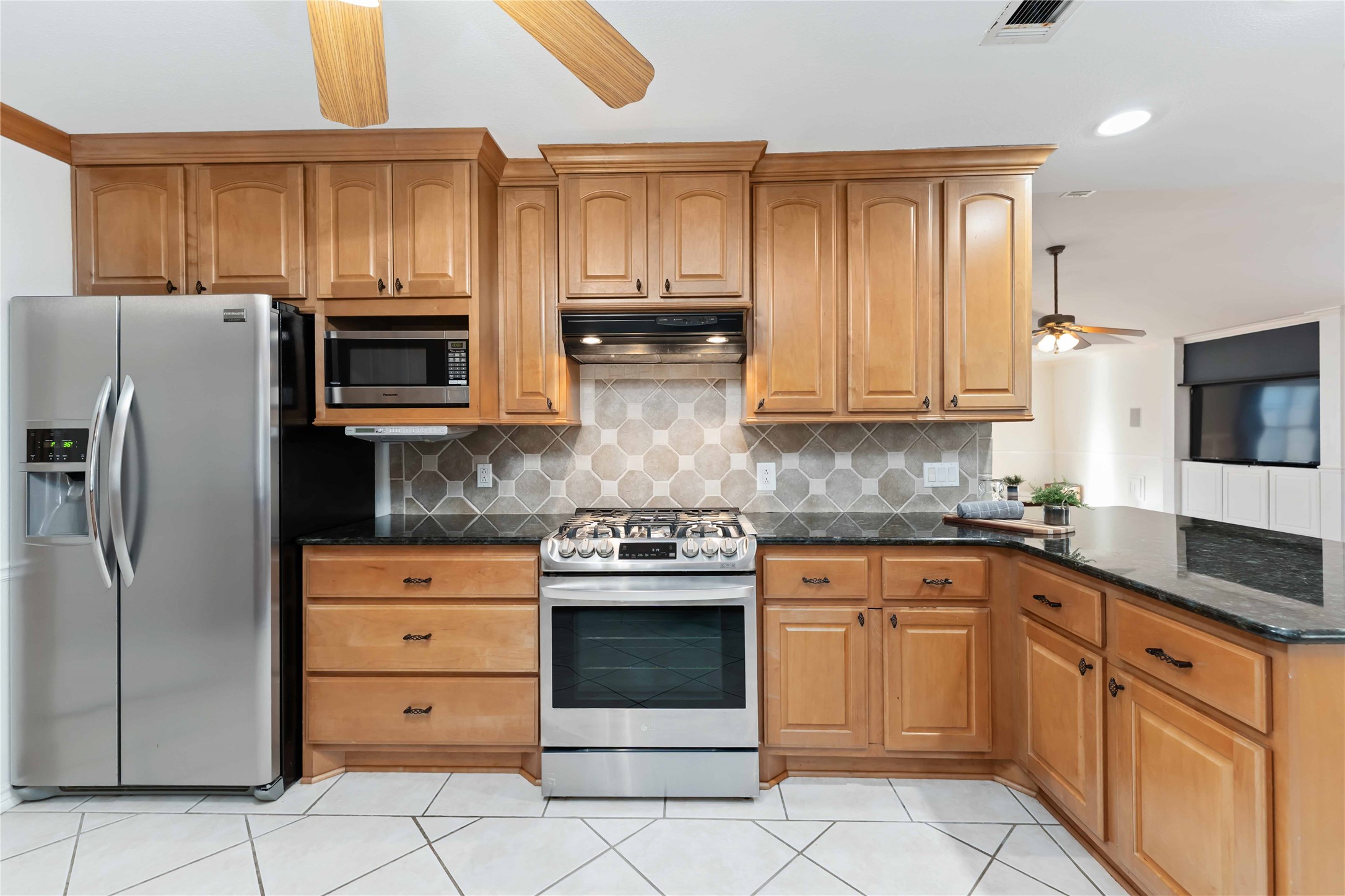 It offers ample counter space with a dark granite finish and a stylish hexagonal tile backsplash, creating a cozy and functional cooking area.