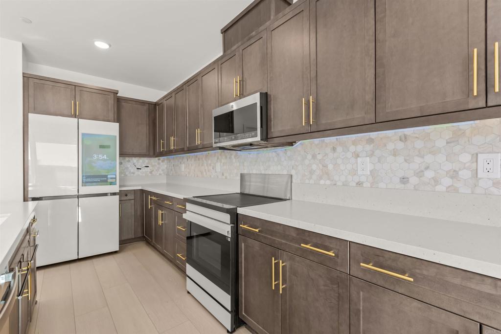 550 Meadowood Street Fallbrook, CA 92028 - Photo 10 of 37 a kitchen with stainless steel appliances granite countertop white cabinets a microwave a sink and a refrigerator