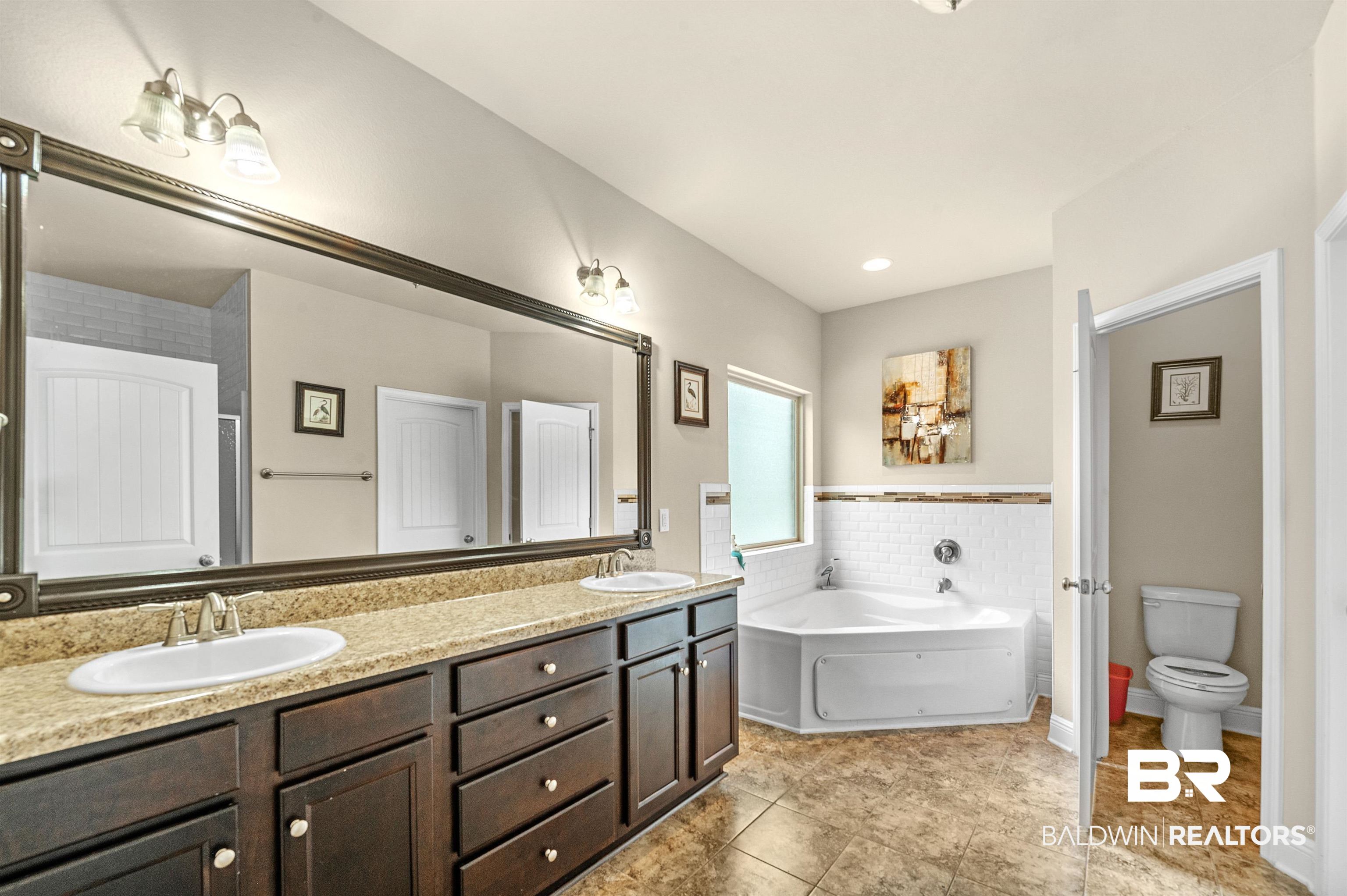 1086 Melbourne Court Foley, AL 36535 - Photo 23 of 43 Bathroom featuring tile patterned flooring, toilet, dual bowl vanity, and a tub