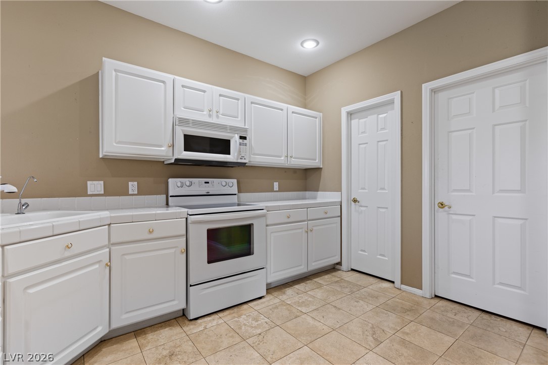 649 Rancho Circle Mesquite, NV 89027 - Photo 23 of 73 This bright kitchen features white cabinetry and tiled floors, creating a pristine and inviting atmosphere.