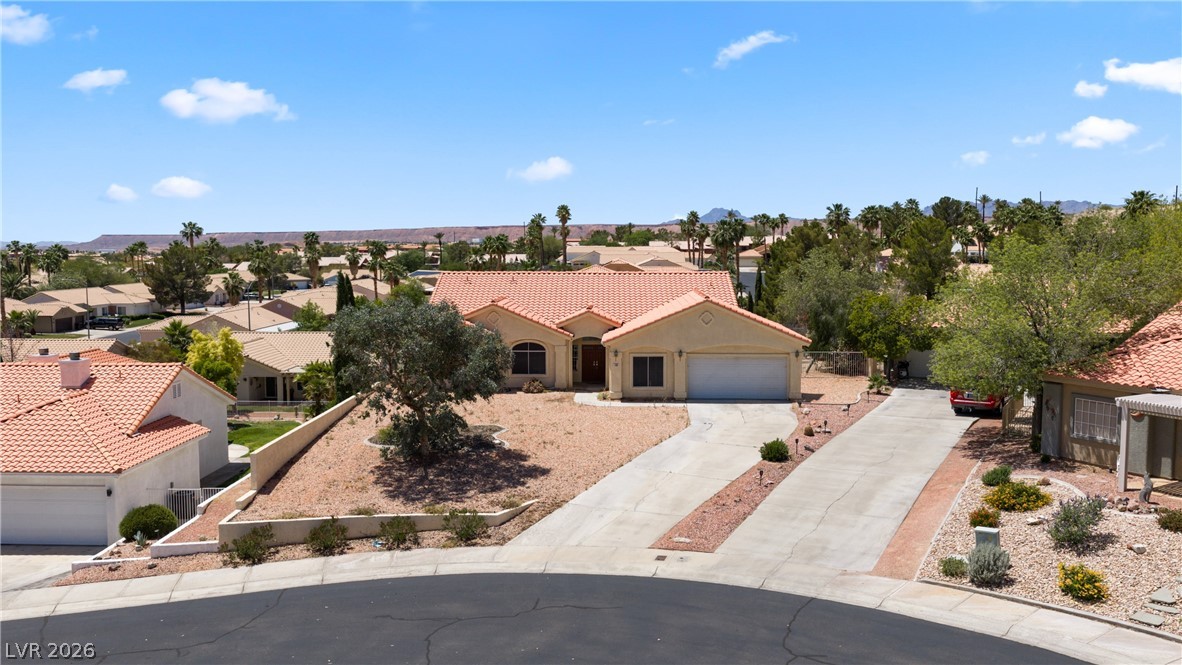 649 Rancho Circle Mesquite, NV 89027 - Photo 64 of 73 This desert home features a tile roof and a private driveway, set against a distant mountain backdrop.