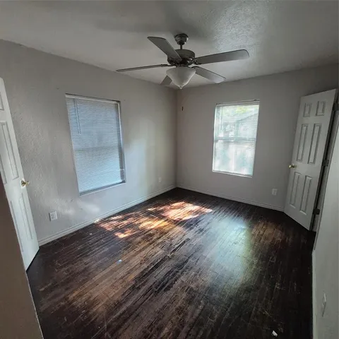 en empty room with wooden floor and windows
