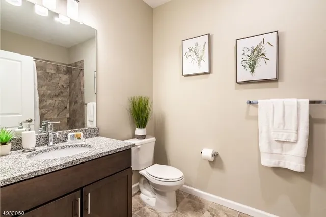 a bathroom with a granite countertop toilet sink and mirror