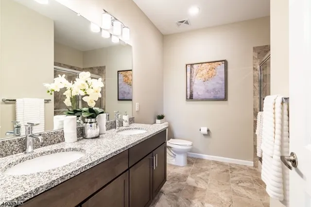 a bathroom with a granite countertop sink mirror vanity and toilet