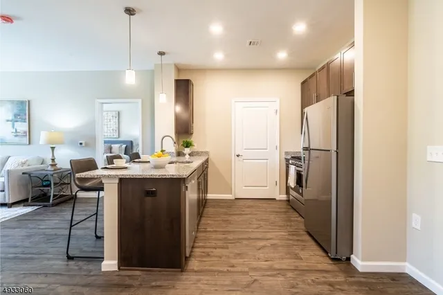 a large kitchen with a center island wooden floor stainless steel appliances and windows