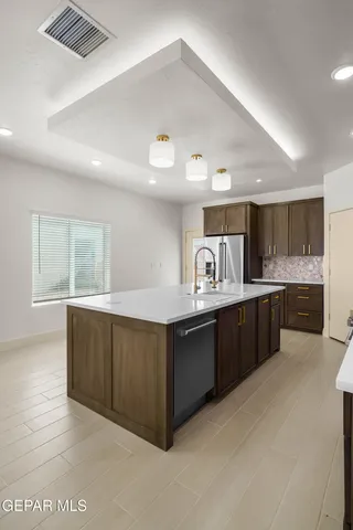 a large kitchen with a large counter top space a sink stainless steel appliances and cabinets