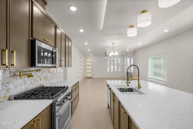 a kitchen with stainless steel appliances granite countertop a sink a stove and a window