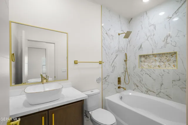 a bathroom with a granite countertop toilet sink and mirror