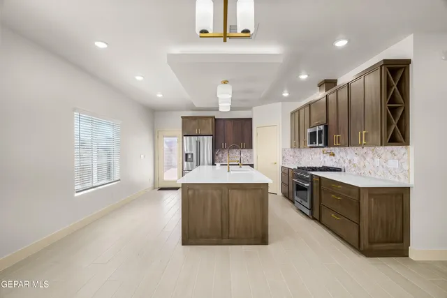 a large kitchen with a large counter top a sink stainless steel appliances and cabinets