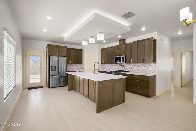 a large kitchen with a large counter top cabinets and stainless steel appliances