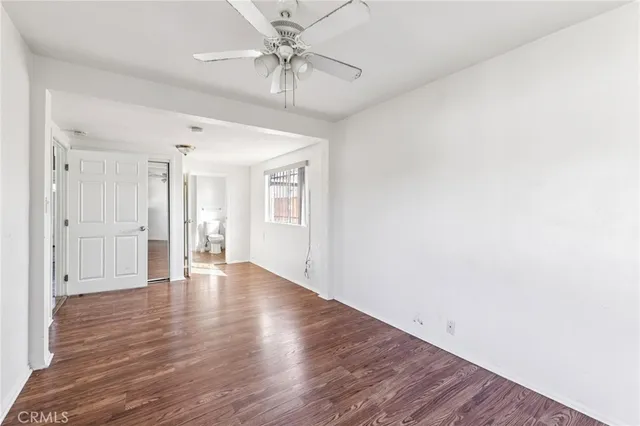 an empty room with wooden floor chandelier fan and windows
