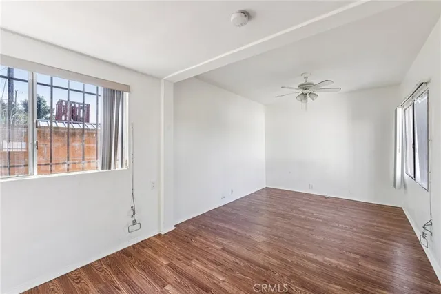a view of empty room with wooden floor and fan