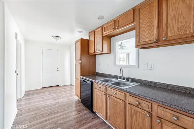 a kitchen with stainless steel appliances granite countertop a sink dishwasher a refrigerator and cabinets with wooden floor
