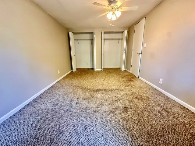 an empty room with a chandelier fan and windows