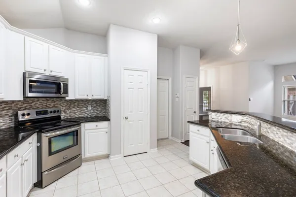 a kitchen with granite countertop white cabinets and stainless steel appliances