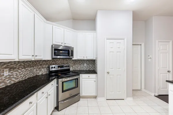 a kitchen with granite countertop a stove and a microwave