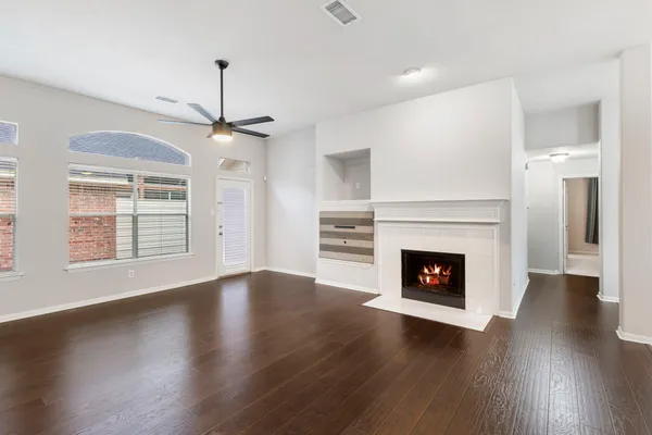 a view of an empty room with wooden floor fireplace and a window