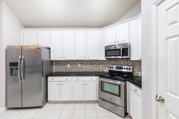 a kitchen with granite countertop white cabinets and stainless steel appliances