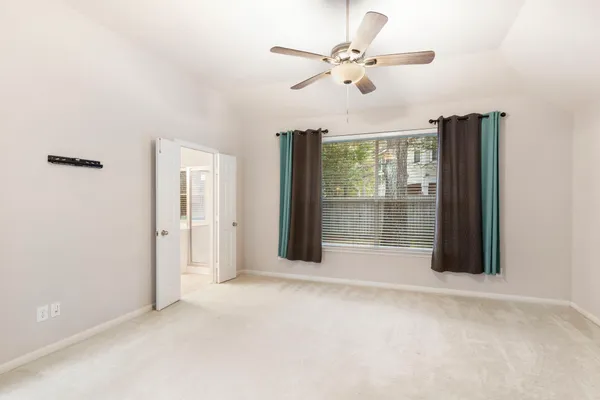 an empty room with windows and ceiling fan