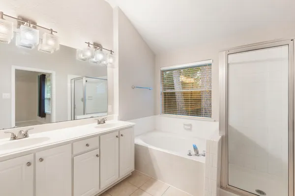 a bathroom with a tub a sink and a large mirror