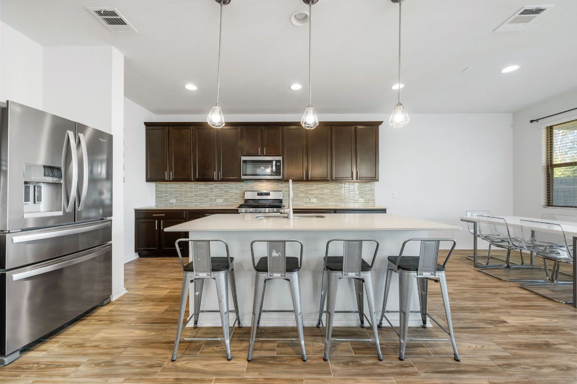 1902 Tasmanian Tiger Trace Austin, TX 78728 - Photo 7 of 29 a kitchen with granite countertop a table chairs stainless steel appliances and wooden floor