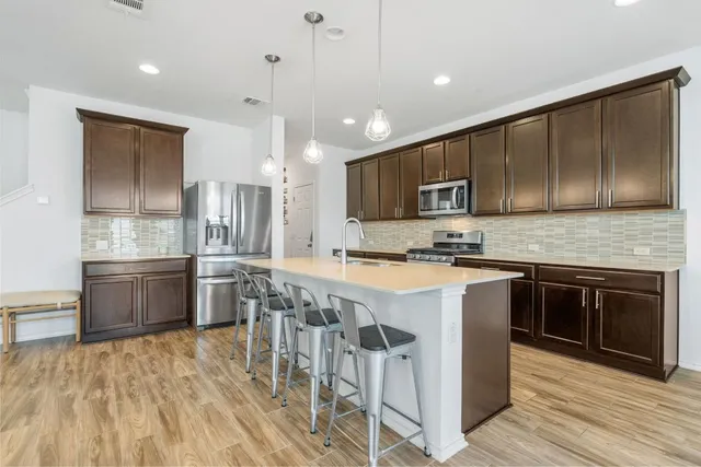 a kitchen with stainless steel appliances granite countertop a stove a sink dishwasher a refrigerator and a microwave oven with wooden floor