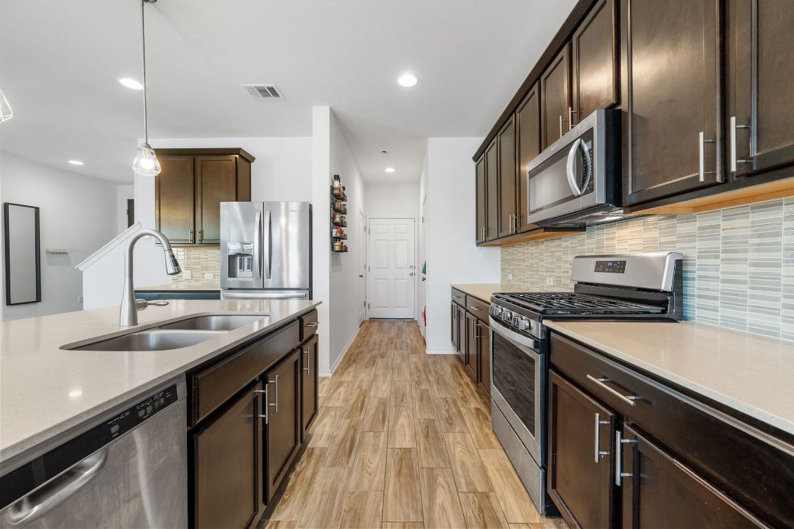 1902 Tasmanian Tiger Trace Austin, TX 78728 - Photo 9 of 29 a kitchen with stainless steel appliances granite countertop a sink a stove and a wooden floors
