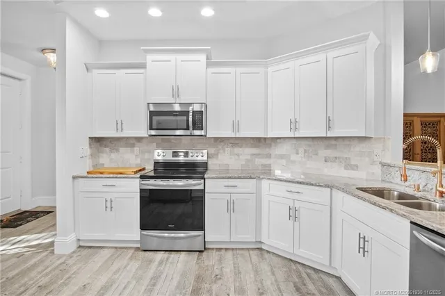 a kitchen with stainless steel appliances granite countertop a stove and white cabinets