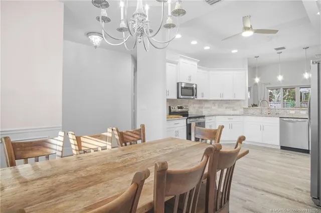 a kitchen with kitchen island a dining table chairs and white cabinets