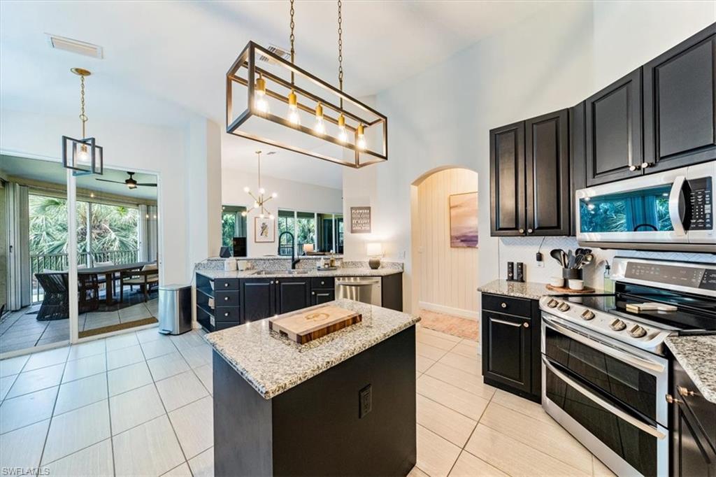 20280 Burnside Place, Unit 1202 Estero, FL 33928 - Photo 10 of 42 a kitchen with stainless steel appliances granite countertop a stove a sink and a microwave
