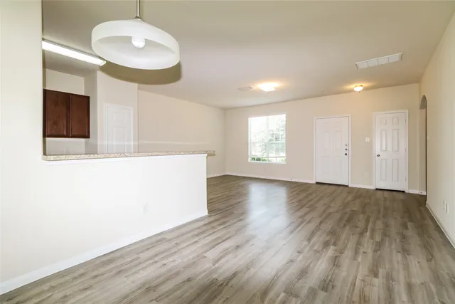 a view of an empty room with wooden floor and a window