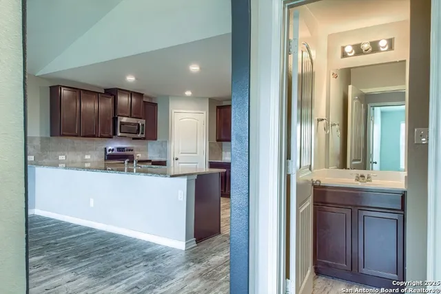 a kitchen with kitchen island granite countertop wooden cabinets a sink and stainless steel appliances